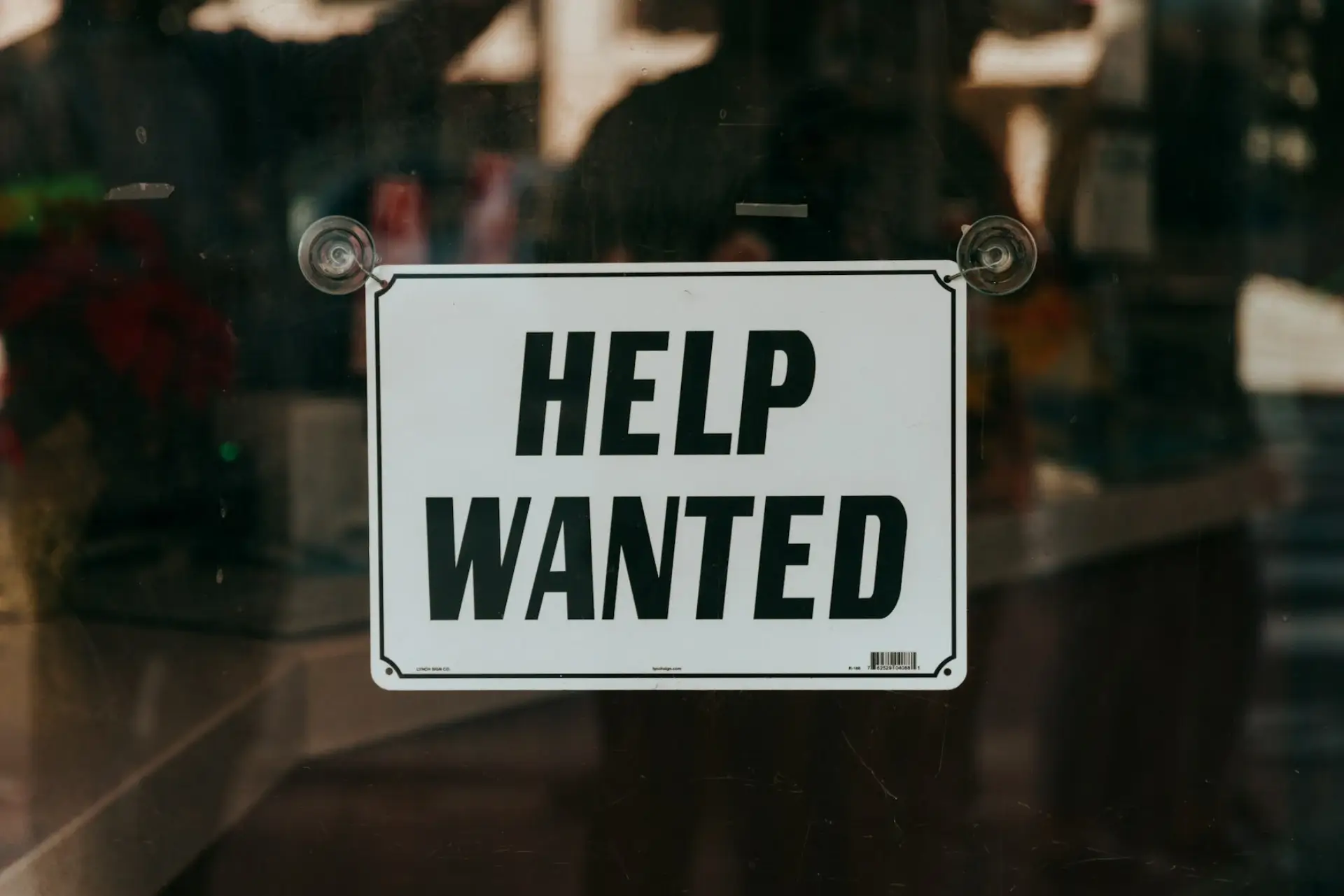 a help wanted sign hanging in a window